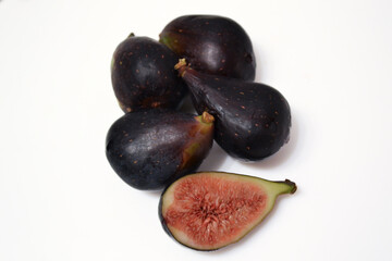 Four fresh  black blue figs, one half on wite background