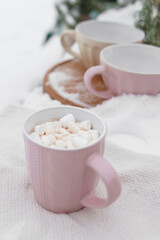Pink mug of hot chocolate with marshmallow on snow. Winter drink for Christmas and New Year holiday celebration. Cozy warm beverage in mug.