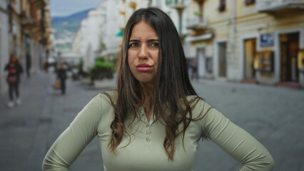 Fototapeta premium Young woman with a puzzled expression on a bustling street, indicating confusion in an urban setting surrounded by people and buildings under a clear sky.