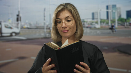 Woman judge holds open book on street with focused gaze amid blurred city traffic and highrise towers; justice.