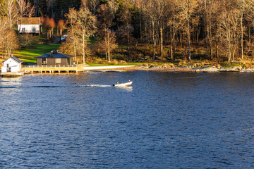 Obraz premium Speeding Boat Past a Modern Waterside Property