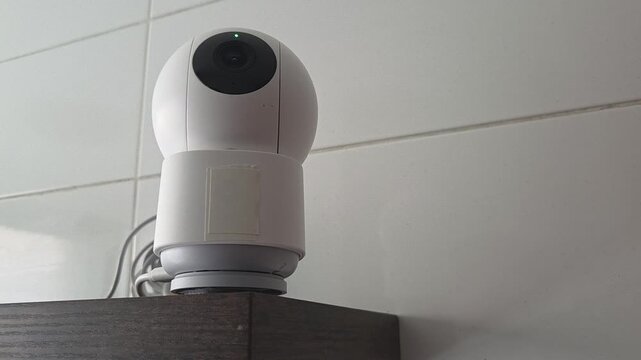 Security camera - initializes the start-up test, the purple and green indicators light up, the blue indicator blinks, makes a turn, the blue indicator lights up. Modern security camera rotation