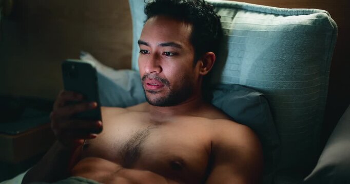 Man, phone and internet in bed for temptation, self pleasure and masturbation in home. Night, secret and person with smartphone for pornography, addiction and aroused activity in bedroom of apartment