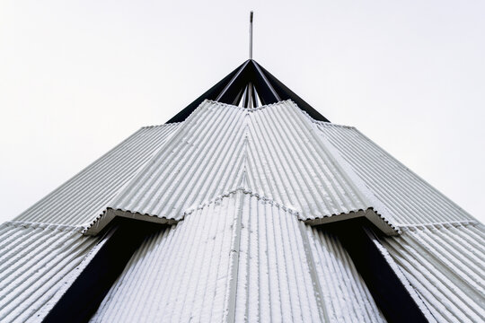 View of striking geometric architecture with corrugated silver panels and stark black accents reaching toward the sky, Reynisfjara Beach, Vik, Iceland.