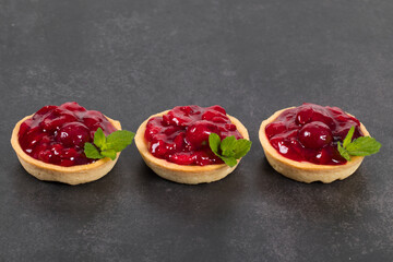 Vegan Cherry Round tartlets. With cream and mint. Dark gray background