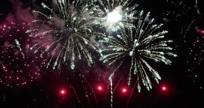 A vibrant golden fireworks display illuminating the night sky over a calm water surface, reflecting bursts of golden light, Christmas or New year celebration or countdown