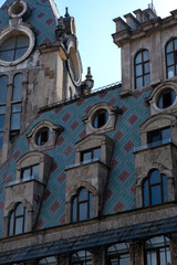 Fototapeta premium Historic architectural tower with ornate roof and windows against blue sky