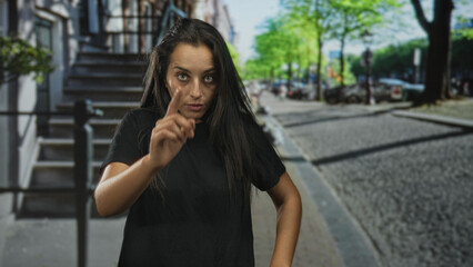 Fototapeta premium Woman with hand to hair standing on city street steps, eyes closed in a relaxed pose; quiet thoughtful.