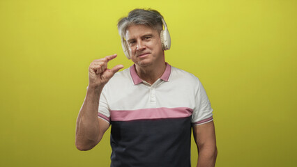 Man wearing headphones pinching thumb and index finger to show small size while wearing a polo...