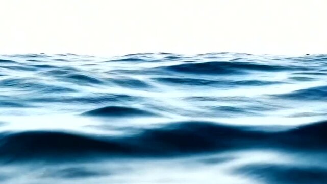 Close-up of ocean waves with gentle ripples on the surface under bright white sky
