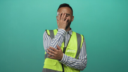 Young man wearing reflective safety vest and striped shirt laughing with clasped hands in studio...