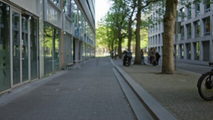 Urban european town with blurred background, defocused trees, roads, buildings, people and bokeh effect creating a serene outdoor city atmosphere.