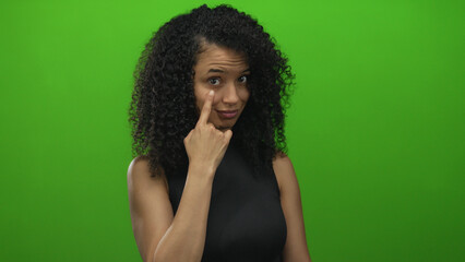 Woman gestures thoughtfully against a vibrant green background, conveying emotion and expression.
