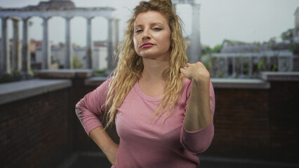 Woman pinches nose with fist while other hand rests on hip near terrace railing on building rooftop; disgust defiance.