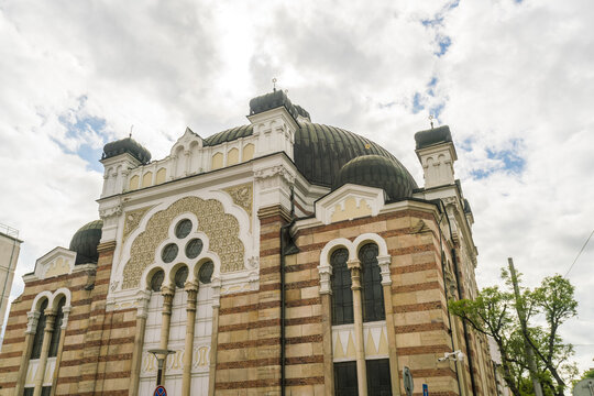 View of a striking architectural marvel, the synagogue rises with its striped brickwork and ornate details against a soft, cloudy sky, Sofia, Sofia City Province, Bulgaria.