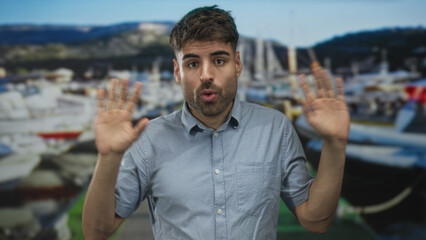 Fototapeta premium Man in blue shirt talking and gesturing with raised hands beside boat at building; curiosity exploration discovery.