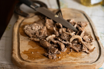 Butcher's Kitchen: Cutting Slices of Cooked Delicacy on a Dark Wooden Chopping Board.