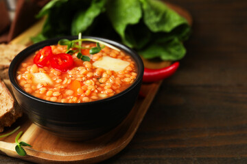 Delicious lentil soup with vegetables served on wooden table, closeup. Space for text