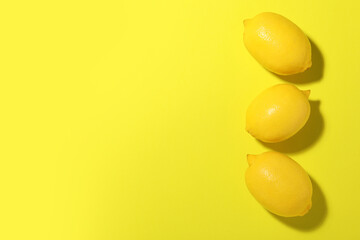 Fresh ripe lemons on yellow background, flat lay. Space for text
