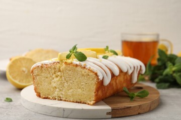 Delicious lemon cake with glaze, fresh fruit slices and mint on gray table, closeup
