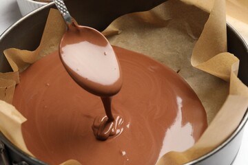 Taking liquid chocolate dough with spoon from baking dish, closeup