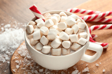 Christmas atmosphere. Tasty cocoa with marshmallows and candy canes on table, closeup