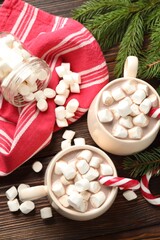 Tasty cocoa with marshmallows, candy canes and Christmas decor on wooden table, flat lay