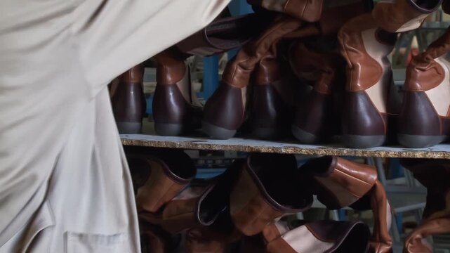Worker Performing Quality Control on Finished Boots in Shoe Factory