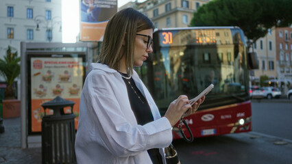Young woman texting on smartphone with hands, wearing glasses and a white shirt on a rome street while looking at screen; urban concentration.