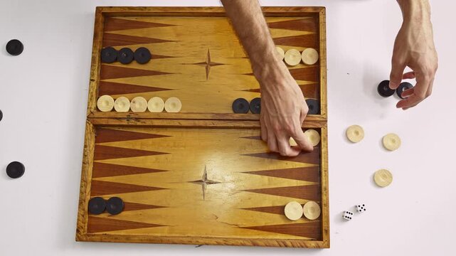 Observe the meticulous setup of a classic backgammon board as hands place the game pieces. This traditional tabletop activity promises a fun and strategic experience for players.