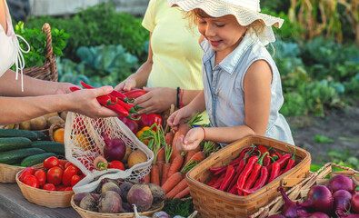Family at a farmers market with vegetables. Selective focus.