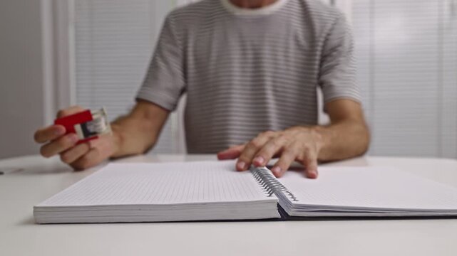 A person repeatedly stamps a date onto blank pages of a spiral-bound notebook.
