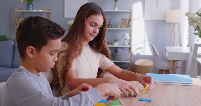 Happy children, brother and sister, friendly at home enjoy playing carefully wood cube board game together, cute little daughter, son sitting at desk, engaged in game activity, developing skills