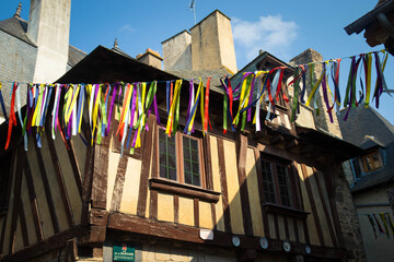 Colorful garlands hanging in old town center of Vitr&eacute;, Brittany, France, with half timbered houses and blue sky in the background.