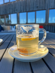 Hot tea with lemon in a clear glass outdoor. Cozy winter atmosphere 
