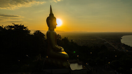 Aerial view at sunset above the Mekong river in Laos revealing Pakse city golden giant buddha
