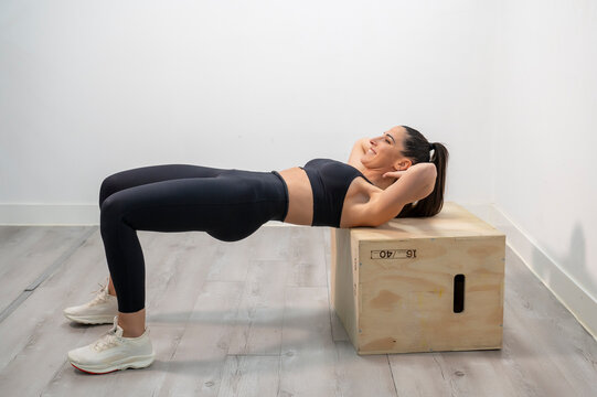 Woman performing hip thrust exercise on plyo box