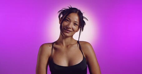 Obraz premium A young Korean model poses in a studio lit by pink neon lights