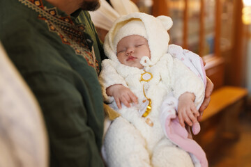Father holding his child during baptism ceremony in church, closeup