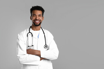 Smiling doctor in medical uniform with stethoscope on grey background. Space for text