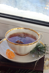 A cup of hot black tea on the windowsill. Christmas atmosphere.