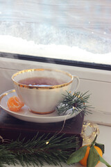 A cup of hot black tea on the windowsill. Christmas atmosphere.