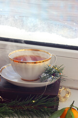 A cup of hot black tea on the windowsill. Christmas atmosphere.