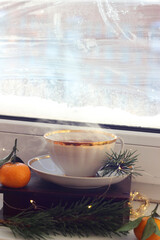 A cup of hot black tea on the windowsill. Christmas atmosphere.