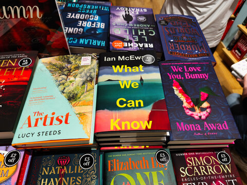 Colorful stack of contemporary paperback books on a bookstore table featuring What We Can Know by Ian McEwan