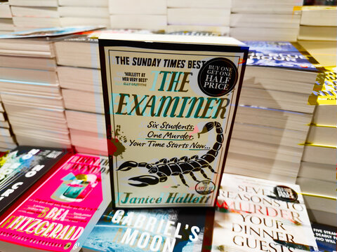The Exterminer by Janice Hallett on display among stacked books at a bookstore