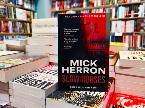 Book display of Mick Herron Slow Horses in a busy bookstore with colorful shelves