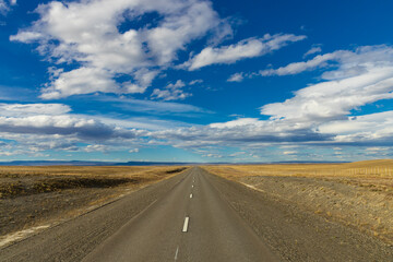 Asphalt road leading to the distant horizon across flat terrain, featuring travel infrastructure, scenic transport route, mobility concept, open landscape perspective ideal for journey themes pathways © Yuliia