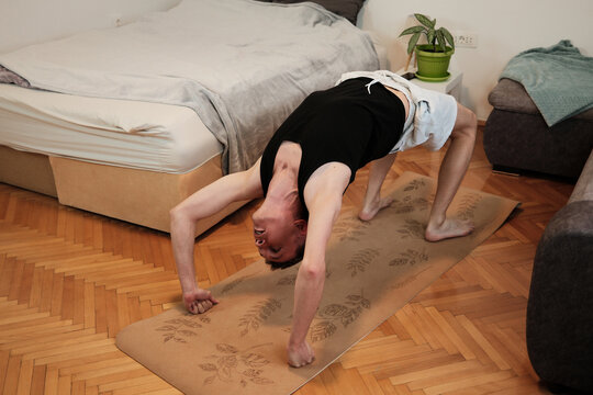 A man performs a bridge pose on a yoga mat at home. The moment expresses active stretching concept. - Powered by Adobe