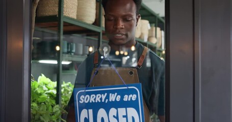 Relief, closed sign and black man by door in store for sustainability, plants or greenery at small business. Board, customer service and African botanist with signage at eco friendly nursery.